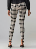 Woman wearing beige and black plaid fitted leggings with ankle straps and black blouse viewed from behind