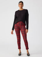 Woman wearing red plaid fitted leggings paired with a black ribbed sweater and black ballet flats in casual style