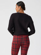 Woman wearing black ribbed sweater and red plaid fitted leggings from the back in women's clothing style
