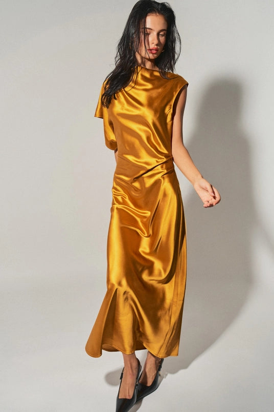 Woman wearing a gold satin asymmetrical maxi dress with one cap sleeve, posing against a plain background.