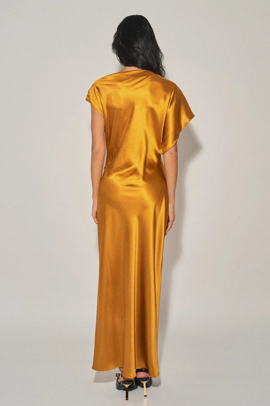 Woman wearing a mustard satin maxi dress with asymmetrical sleeves and a smooth flowing back design