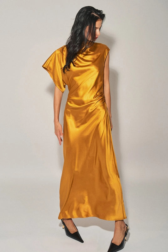 Woman wearing a golden satin asymmetrical maxi dress with cowl neckline and single cap sleeve in women's clothing.