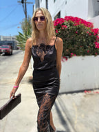 Woman wearing black satin tank with lace details walking outdoors on sunny day with sunglasses and clutch bag