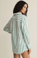 Woman wearing a long-sleeve white shirt with teal vertical stripes, styled as casual women's clothing looks.