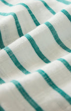 Close-up of soft white fabric with green stripes, part of a women's clothing shirt textile.