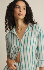 Woman wearing a lightweight striped shirt with green vertical lines, styled casually with sleeves rolled up.