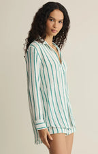 Woman wearing a long-sleeve white shirt with vertical green stripes in a relaxed fit for women's clothing.