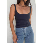 Woman wearing a fitted black scoop neck tank top paired with light blue denim jeans, casual women's clothing style.