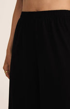 Close-up of a woman wearing black wide flare pants with an elastic waistband in a relaxed fit style