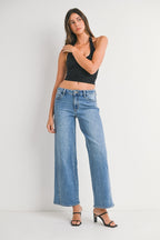 Woman wearing high-waist wide-leg jeans with seamed detail and black sleeveless crop top in casual pose