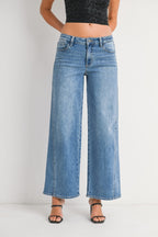 Woman wearing high-waist wide-leg blue jeans paired with black strappy heels and a black crop top