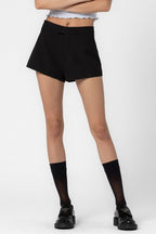 Woman wearing black lined shorts with button and zip closure, paired with black socks and black shoes