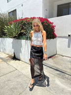 Woman wearing a black sheer overlay midi skirt paired with a white crochet sleeveless top outdoors on a sunny day