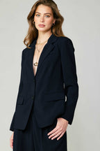 Woman wearing a fitted black single-breasted blazer with welt pocket detail in women's clothing style