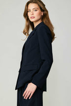 Woman wearing a fitted single-breasted navy blazer with welt pockets in a smart casual style