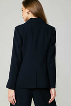 Woman wearing a fitted black single-breasted blazer with welt pocket detail from the back in women's clothing.