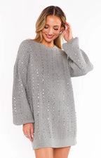 Woman wearing a grey knit sweater dress with sequin details and long sleeves, styled for women's clothing fashion.