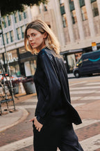 Woman wearing a black pinstripe blouse walking on a city street, showcasing stylish women's clothing.