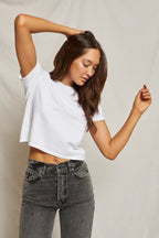 Woman wearing a white midweight cropped tee paired with high-waisted black jeans in a casual pose