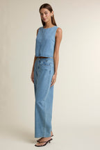 Woman wearing light blue high-waisted denim pants paired with a sleeveless denim crop top and black sandals
