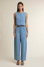 Woman wearing sleeveless cropped denim top and high-waisted wide-leg denim pants in casual outfit