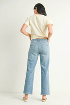 Woman wearing light blue stretchy straight-leg jeans with a mid-rise waistband and a cream short-sleeve top.