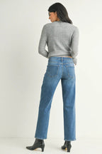 Woman wearing mid-rise straight-leg blue jeans and a gray long-sleeve top, styled with black ankle boots.