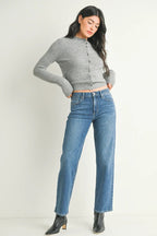 Woman wearing mid-rise straight-leg blue jeans paired with a gray fitted button-up sweater and black ankle boots