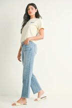 Woman wearing light blue mid-rise straight-leg jeans with a stretchy fit paired with a casual cream t-shirt