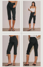 Woman modeling black stretch capri pants paired with a white tank top and black heeled sandals in studio.