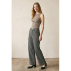 Woman wearing striped straight wide leg jeans paired with a sleeveless taupe top and black heels in a neutral setting