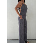 Woman wearing striped wide leg jeans and a matching sleeveless top with side cut-out details posing against white wall