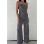 Woman modeling striped wide leg pants and matching sleeveless top against plain wall background