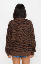 Back view of woman wearing a brown tiger stripe knit sweater with denim shorts