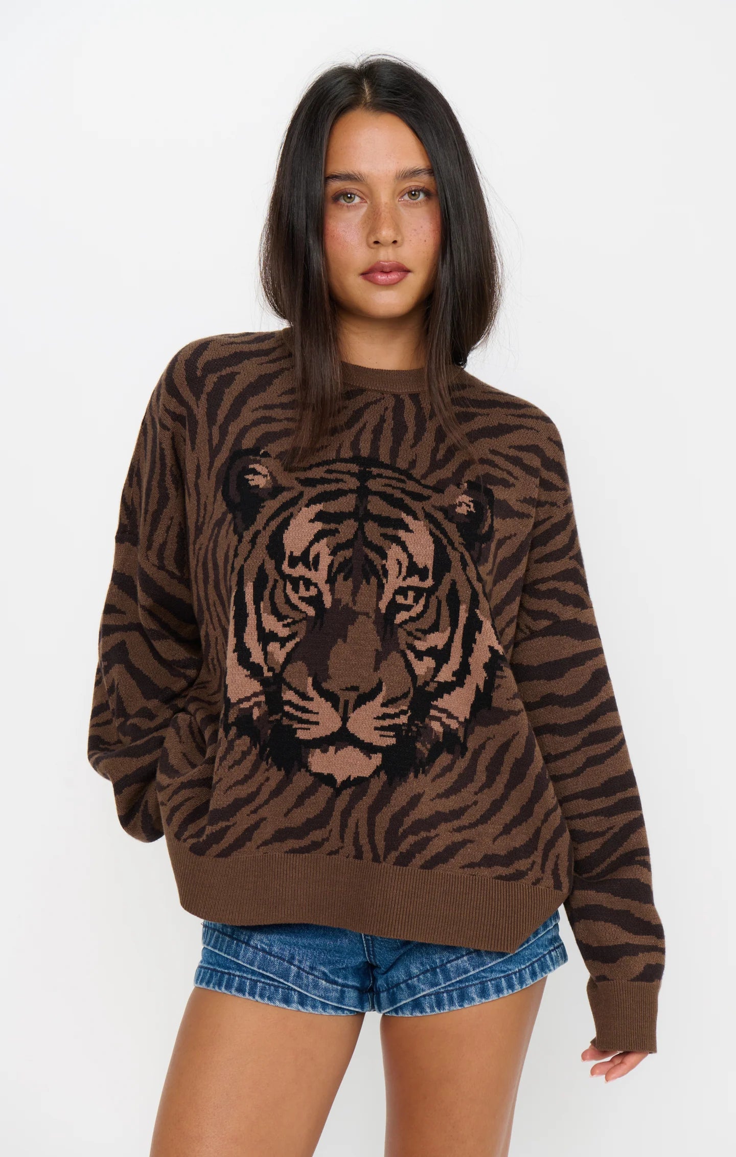 Woman wearing a brown tiger print knit sweater with long sleeves and denim shorts