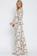 Woman wearing wide-leg flowy pants with botanical toile print in neutral tones, styled with matching top