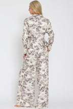 Woman wearing wide-leg flowy pants with beige and brown toile floral print, shown from the back