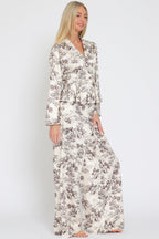 Woman wearing cream wide-leg flowy pants and matching floral print button-up top in women's clothing style