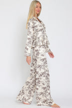 Woman wearing beige and brown toile patterned wide-leg flowy pants with matching top, standing sideways.