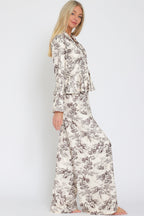 Woman modeling cream and brown floral wide-leg flowy pants with matching long-sleeve top in profile view