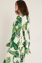 Woman wearing a long sleeve button down top with green tropical leaf print in women's clothing style