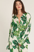 Woman wearing long sleeve button down top with green tropical leaf print, part of women's clothing collection.