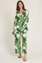 Woman wearing a white long sleeve button down top with green leaf print paired with matching pants in women's clothing.