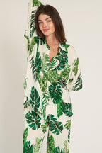 Woman wearing long sleeve button down top with green leaf print, styled as part of women's clothing outfit.