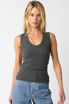 Woman wearing a fitted dark gray ribbed sleeveless top paired with light blue denim jeans.