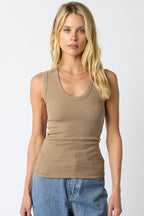 Woman wearing a beige ribbed scoop neck top paired with blue denim jeans in a simple fashion style
