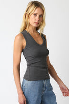 Woman wearing a charcoal ribbed sleeveless top with scoop neckline paired with light blue jeans