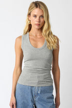 Woman wearing a fitted grey ribbed scoop neck sleeveless top paired with blue denim jeans.