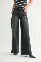 Woman wearing black wide leg jeans paired with a striped sleeveless top and black pointed heels