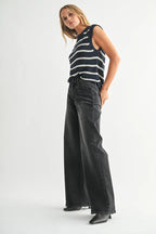 Woman wearing black wide leg jeans paired with a sleeveless navy striped knit top and black boots